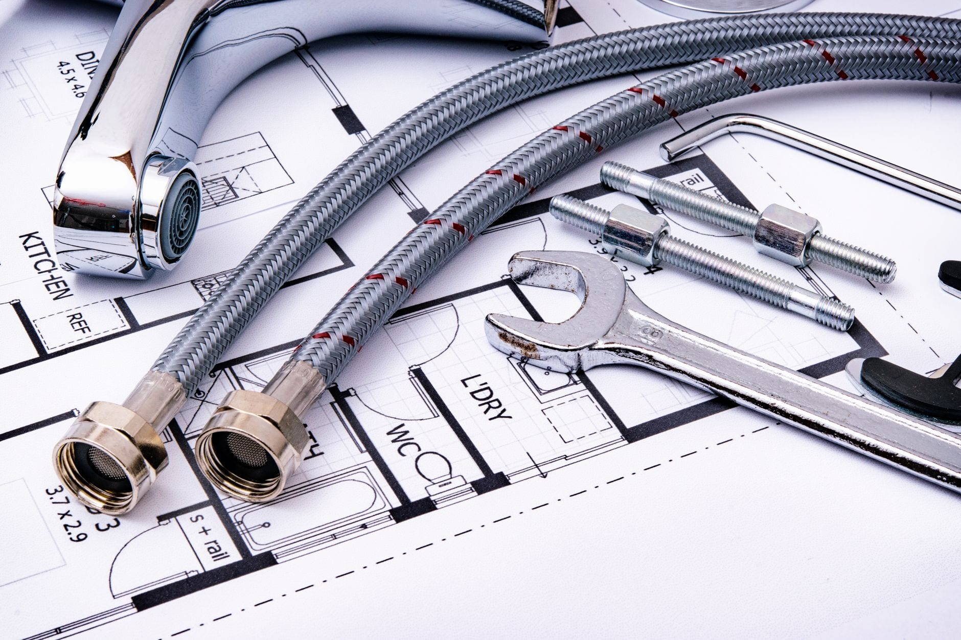 Plumbing fixtures, braided hose lines and a wrench laid out on a floor plan